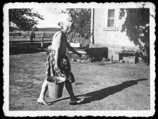 Lucyna Uzarek at her daily chores in the farmyard. Rainwater harvesting vat in the background